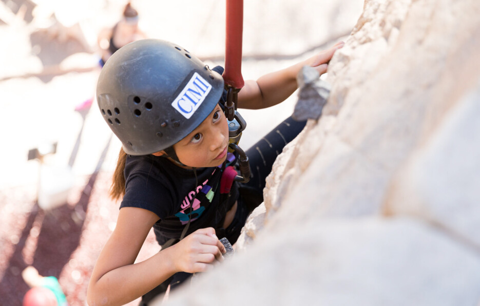 Little girl climbing wall.