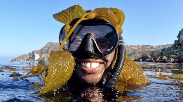 Boy smiling wearing snorkeling gear in water.