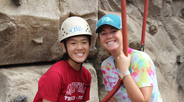 Two girls smiling rockclimbing.