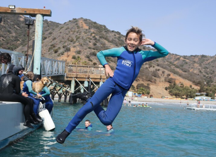 Boy posing and jumping off boat.