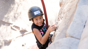 Girl rock-climbing and smiling.