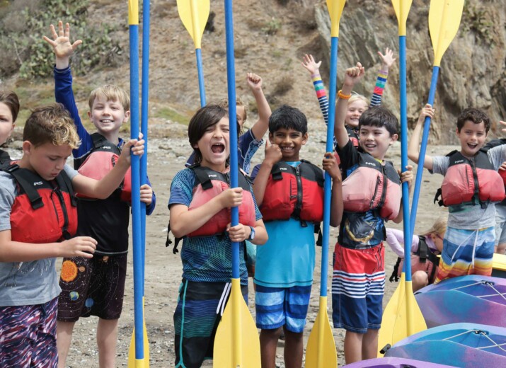 Kids holding kayak paddles.